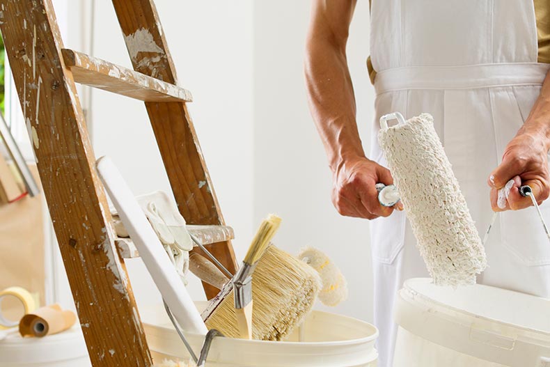 Closeup on the hands and tools of a painter renovating a house.