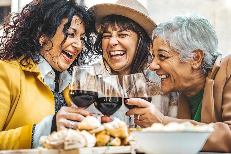 Happy senior women drinking red wine at bar restaurant.