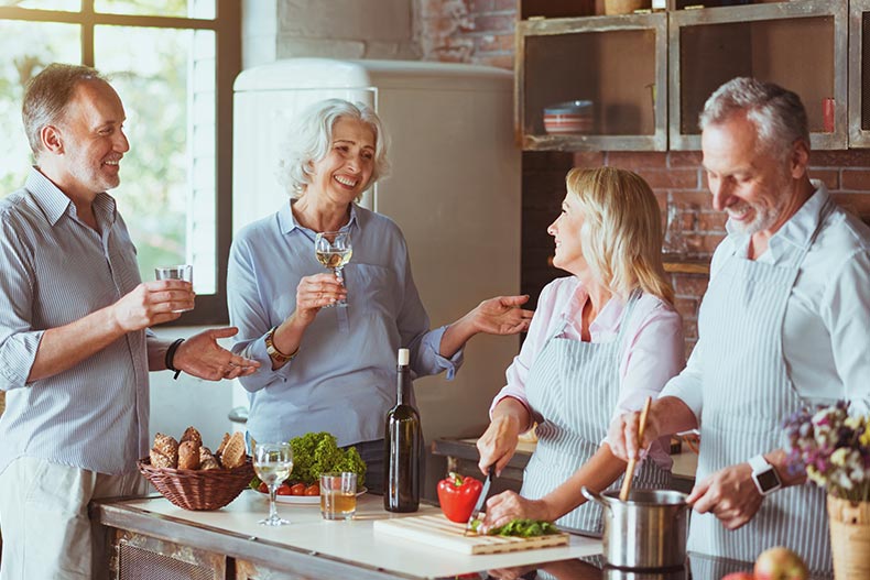 Cheerful baby boomer friends cooking dinner together.