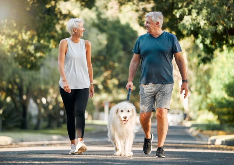 Couple walk dog on a path in a 55+ community.