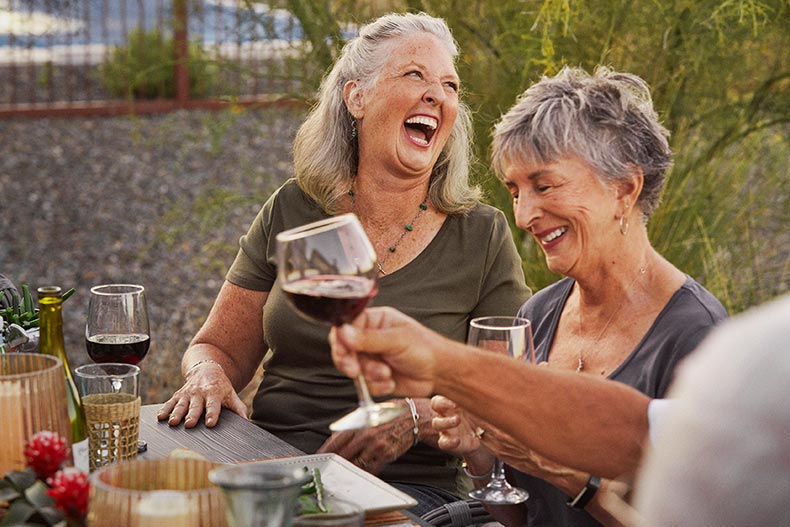 Friends laughing while having an outdoor dinner in their 55+ community.