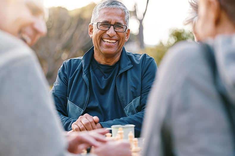 A group of 55+ male friends playing chess in the park.