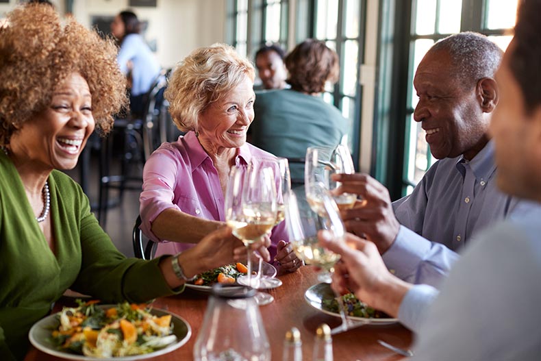 A group of smiling senior friends meeting for a meal in a restaurant.