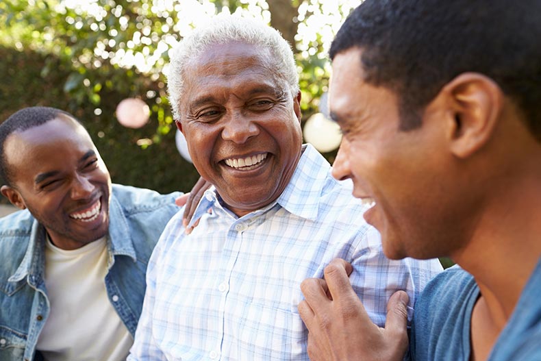 A 55+ man talking with his adult sons in a yard.