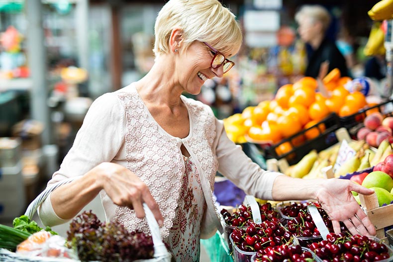 A 55+ woman buying produce at a local market near her 55+ community.