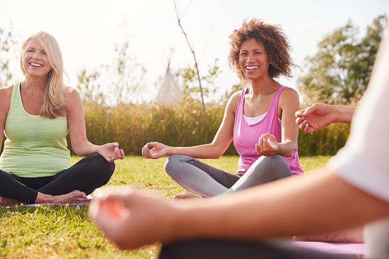 A group of active adults enjoying a yoga class outdoors in their 55+ community.