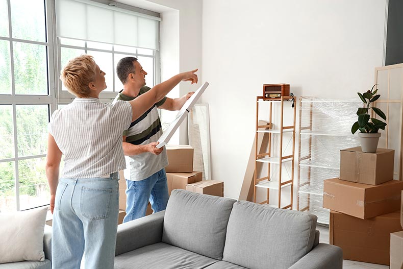 A 55+ couple planning to hang poster in a room on moving day.