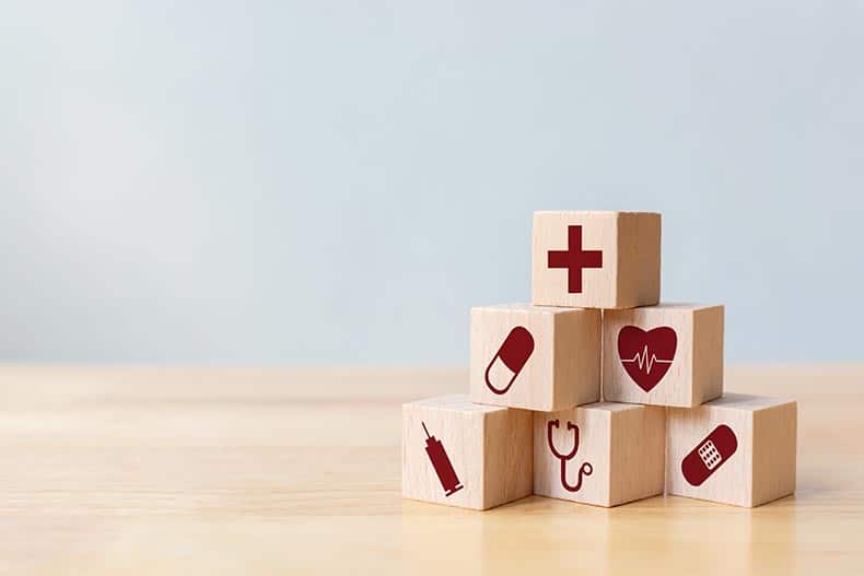A stack of wood blocks with health care and medical icons.