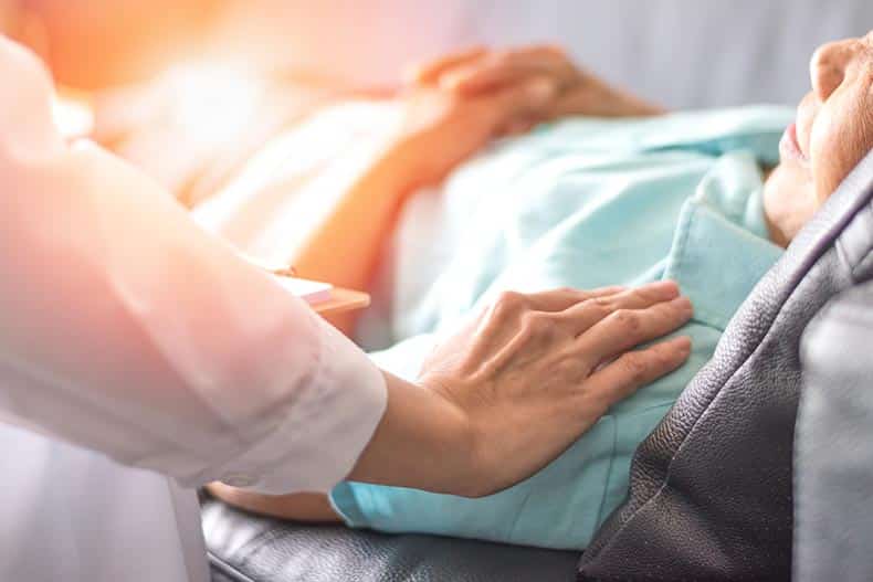 A doctor with their hand on the shoulder of a patient.