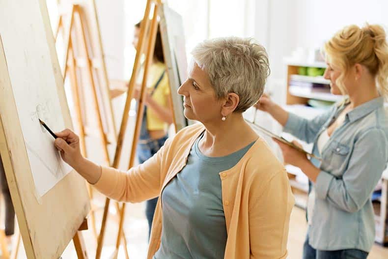 An active adult woman taking an art class in her 55+ community.