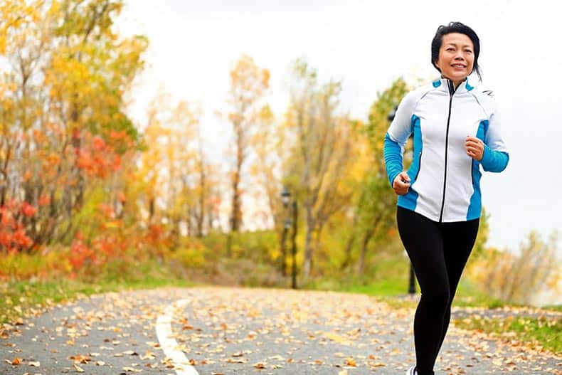 An active adult woman jogging along a path in her 55+ community.