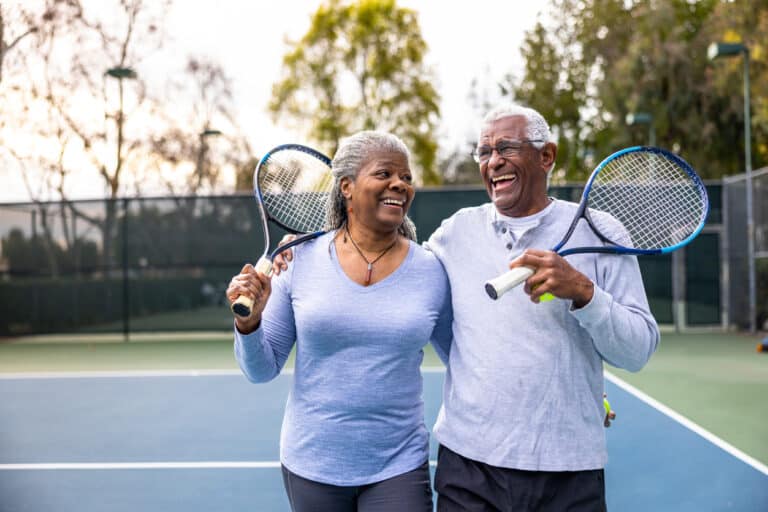 Mature couple plays tennis, enjoying an active adult lifestyle.