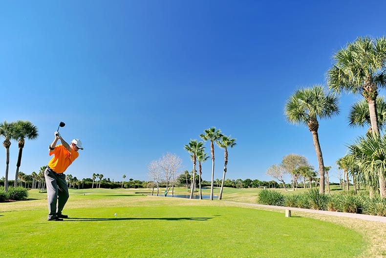 A golfer teeing off on a beautiful Florida golf course.