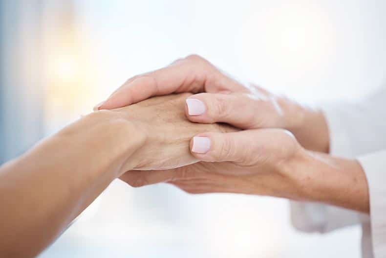 A nurse holding hands with a patient.