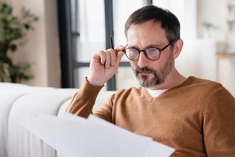 An active adult man carefully reading the HOA rules of his 55+ community.