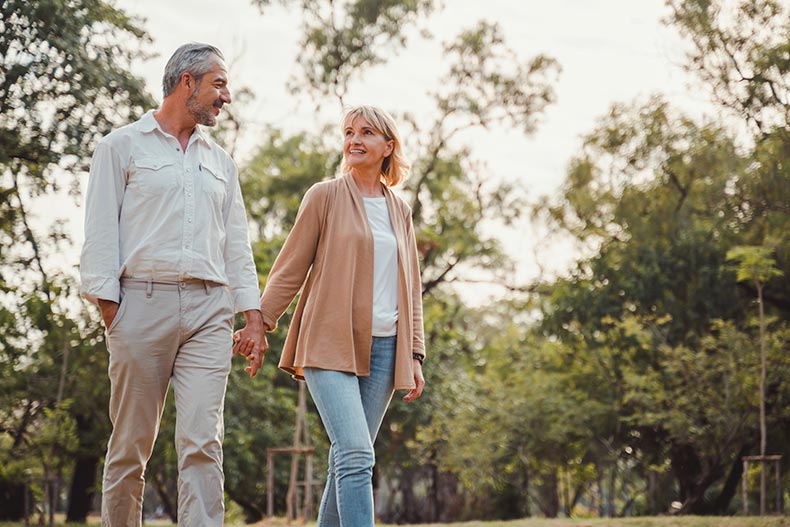 An active adult couple holding hands while touring a 55+ community.