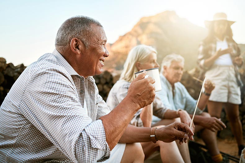 Relaxed 55+ adults camping with friends and drinking a cup of coffee while enjoying retirement.