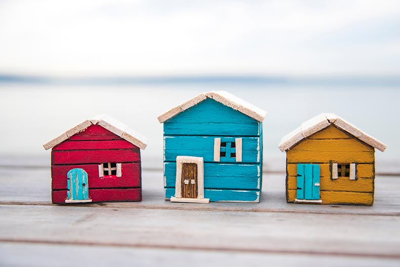 Three tiny model homes side-by-side on a wooden table.