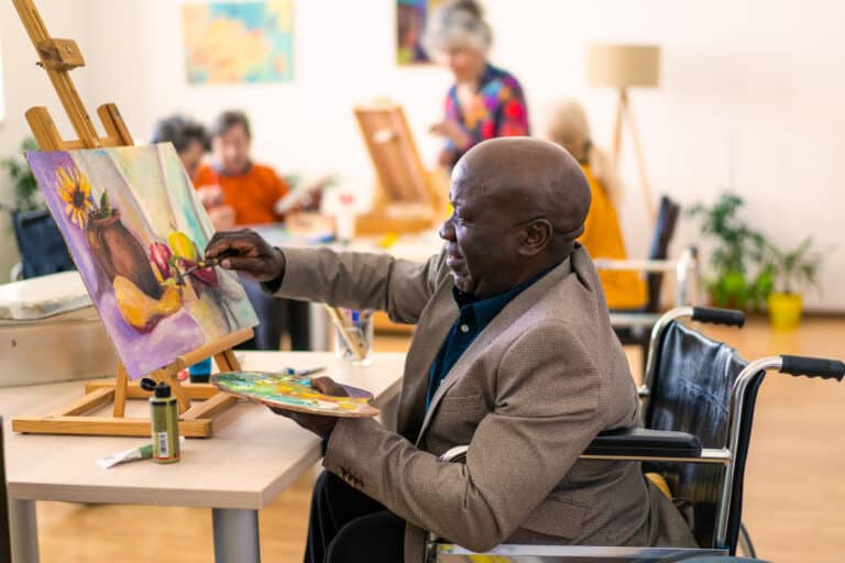 Retired man enjoys a painting class in his retirement community.