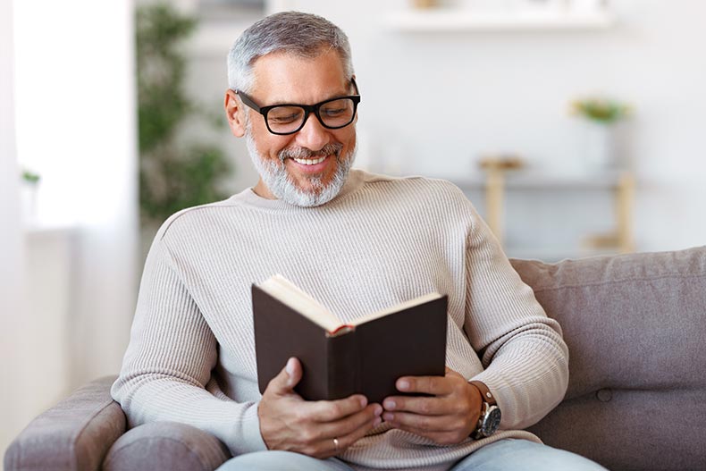 A happy 55+ man reading a book at home.