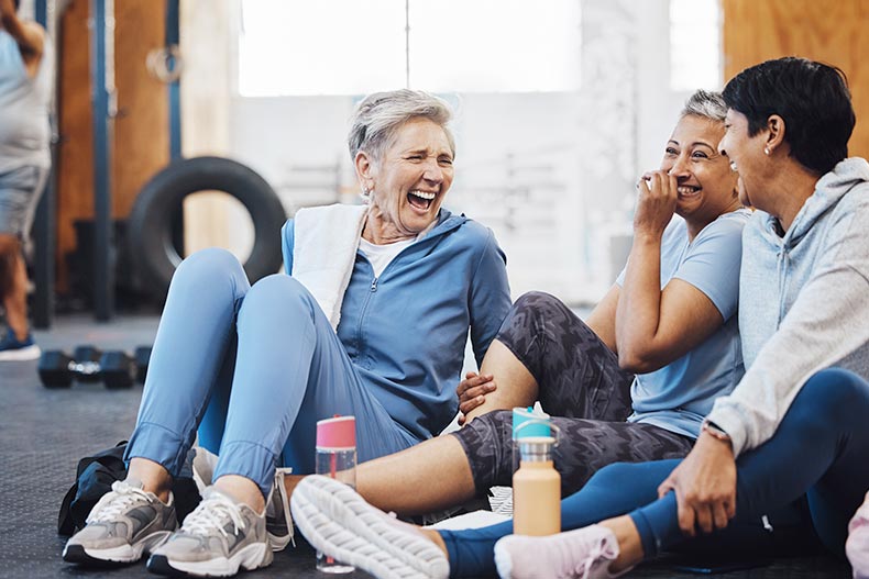 55+ women laughing and smiling in the gym after a fitness class.