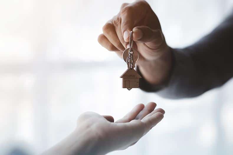 A 55places real estate agent handing over the keys to a new house.