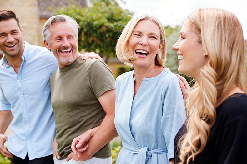 A family with 55+ parents walking and laughing in a garden together.