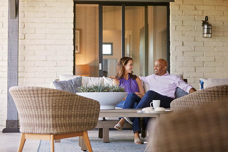 A 55+ couple lounging on the patio of their new home.