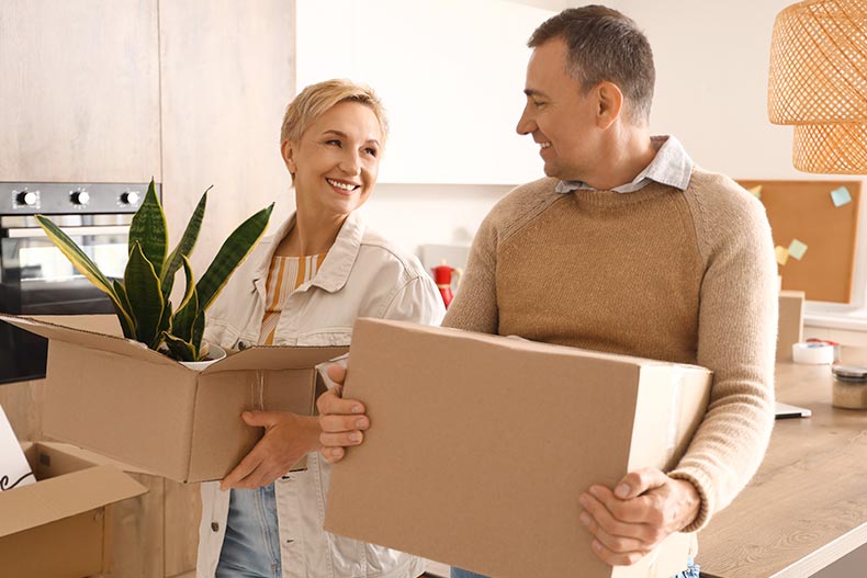 A 55+ couple with cardboard boxes in the kitchen on moving day.