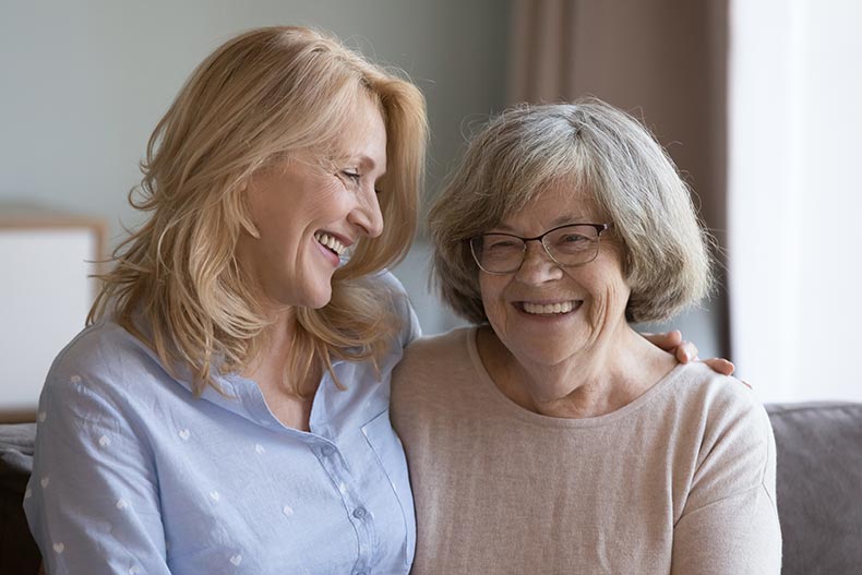 A happy senior mom and middle-aged daughter laughing together.