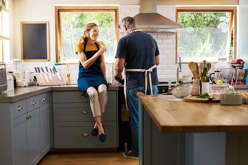 A 55+ couple laughing and cooking in the new home they bought in 2024.