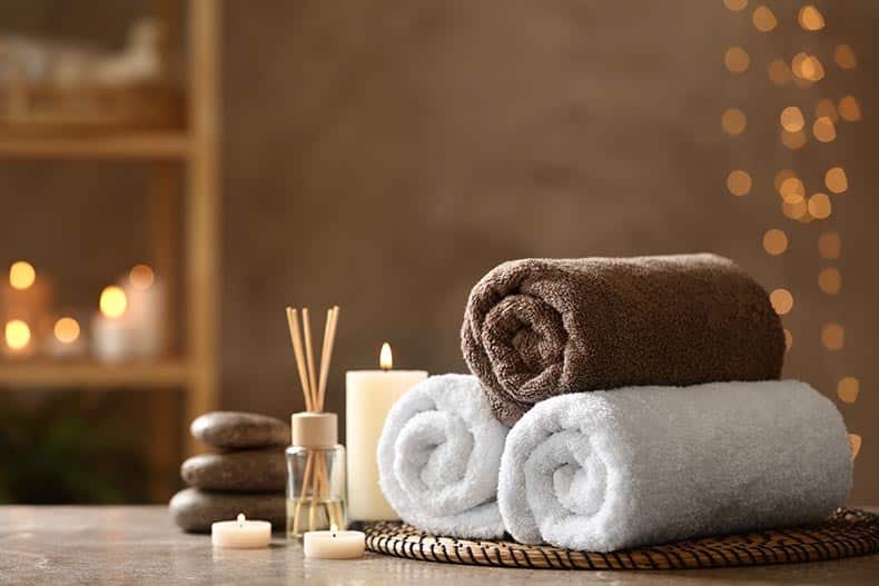 Spa stones and towels on a grey marble table.