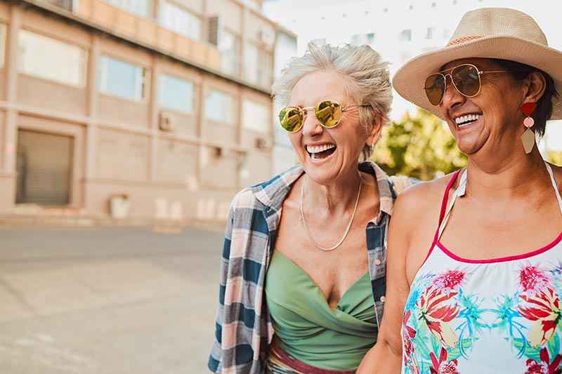 Two 55+ women laughing during their 'stay and play' vacation at a 55+ community.