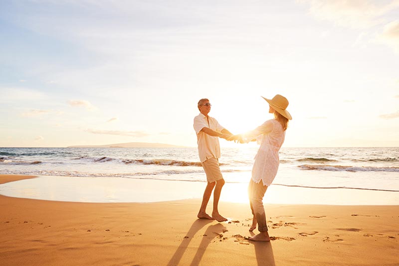 A happy 55+ couple enjoying a sunset on a Florida beach.