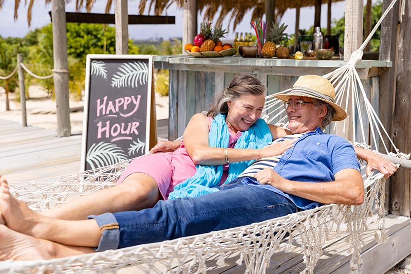 A 55+ couple lounging in a hammock on the grounds of their 55+ community.