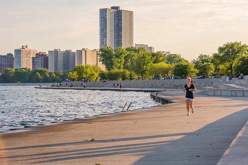 A woman jogging at the park area at Montrose Beach, with the Chicago skyline in the distance.