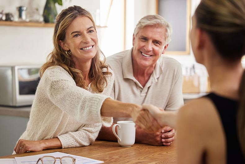 A 55+ homebuyer shaking hands with a Realtor after having her homebuying questions answered.