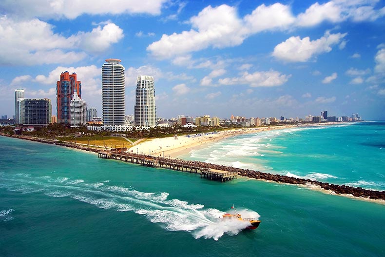 Aerial view of South Miami Beach with a boat cruising next to the city line.