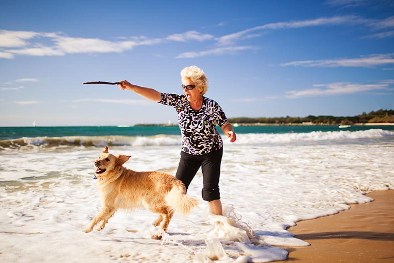 A 55+ woman playing on the beach with her dog in Myrtle Beach, South Carolina.