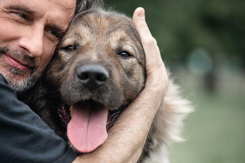 Close-up of a man hugging his dog while on a walk in his 55+ community.