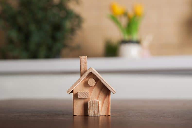 A miniature wooden model of a house on a tabletop.