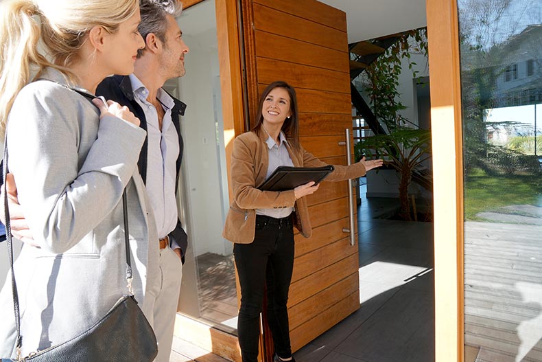 A Realtor giving a 55+ couple a tour of a home and answering all of their questions about the community.