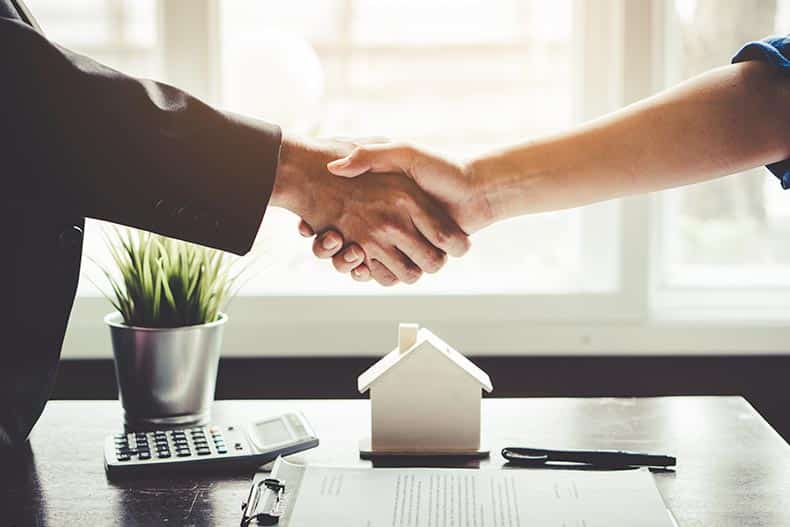 A real estate agent shaking hands with a client and receiving their commission.