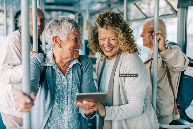 55+ active adults smiling while riding on a bus.