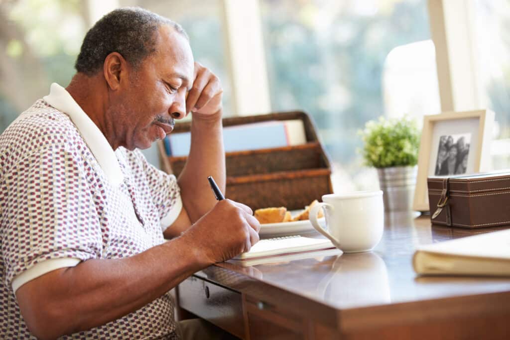 A senior man at his desk taking notes about applying for a reverse mortgage.