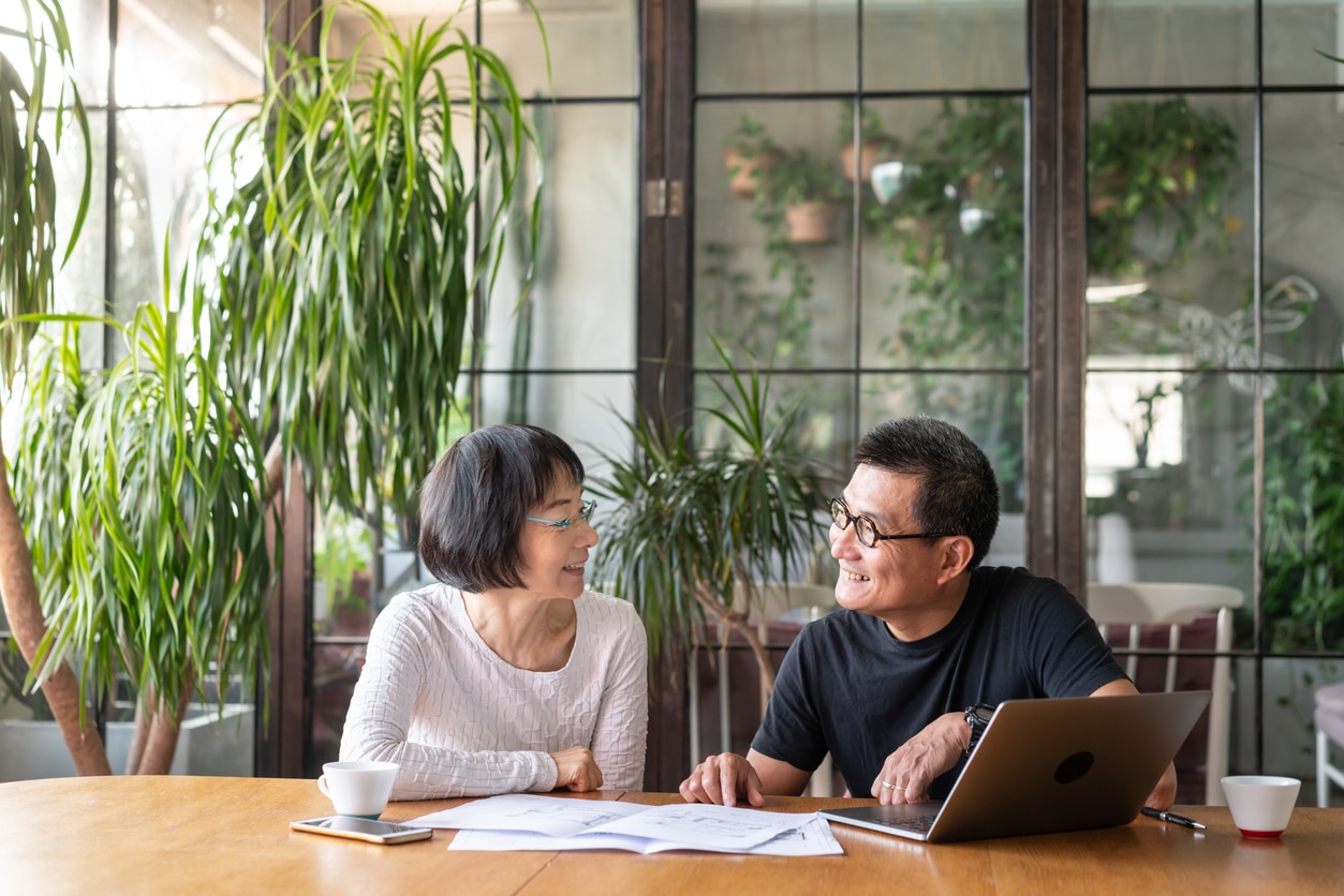 A retired couple sits at a table to discuss estate planning for their 55+ community home.