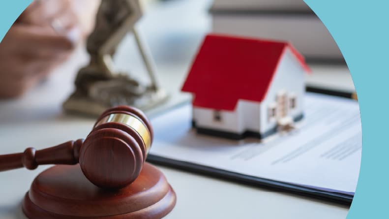 A gavel beside a small model home on top of a document.