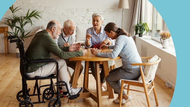 Four 55+ friends sitting at table together and a playing game.
