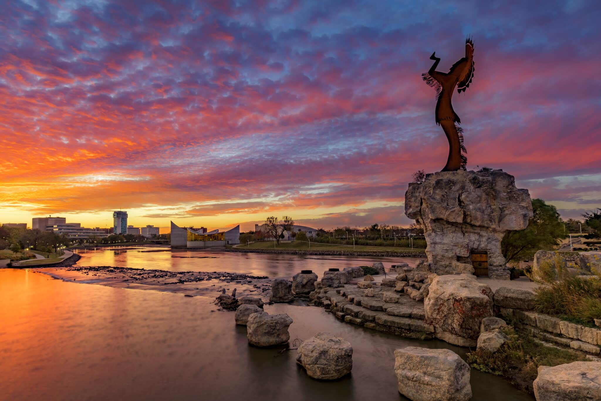 The Keeper of the Plains statue and the Wichita skyline at sunset.