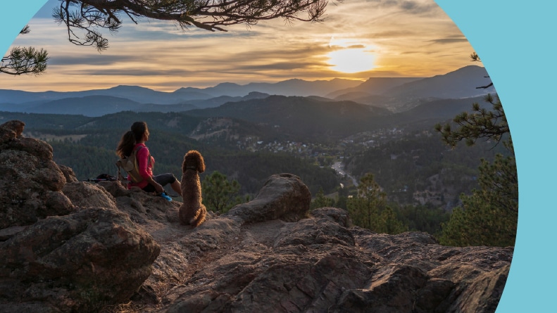 A woman hiking at sunset in the Rocky Mountains of Colorado with her dog.